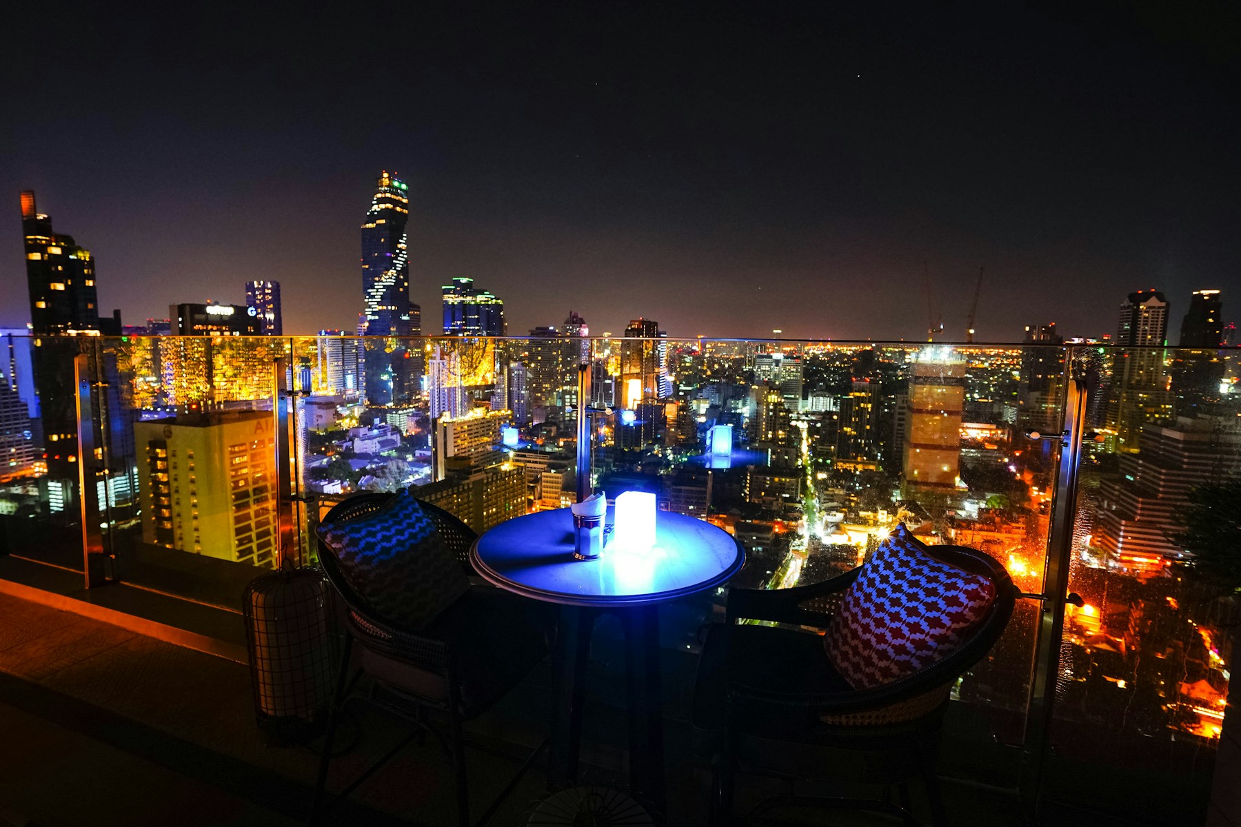 Bangkok skyline glowing at night beyond a rooftop lounge