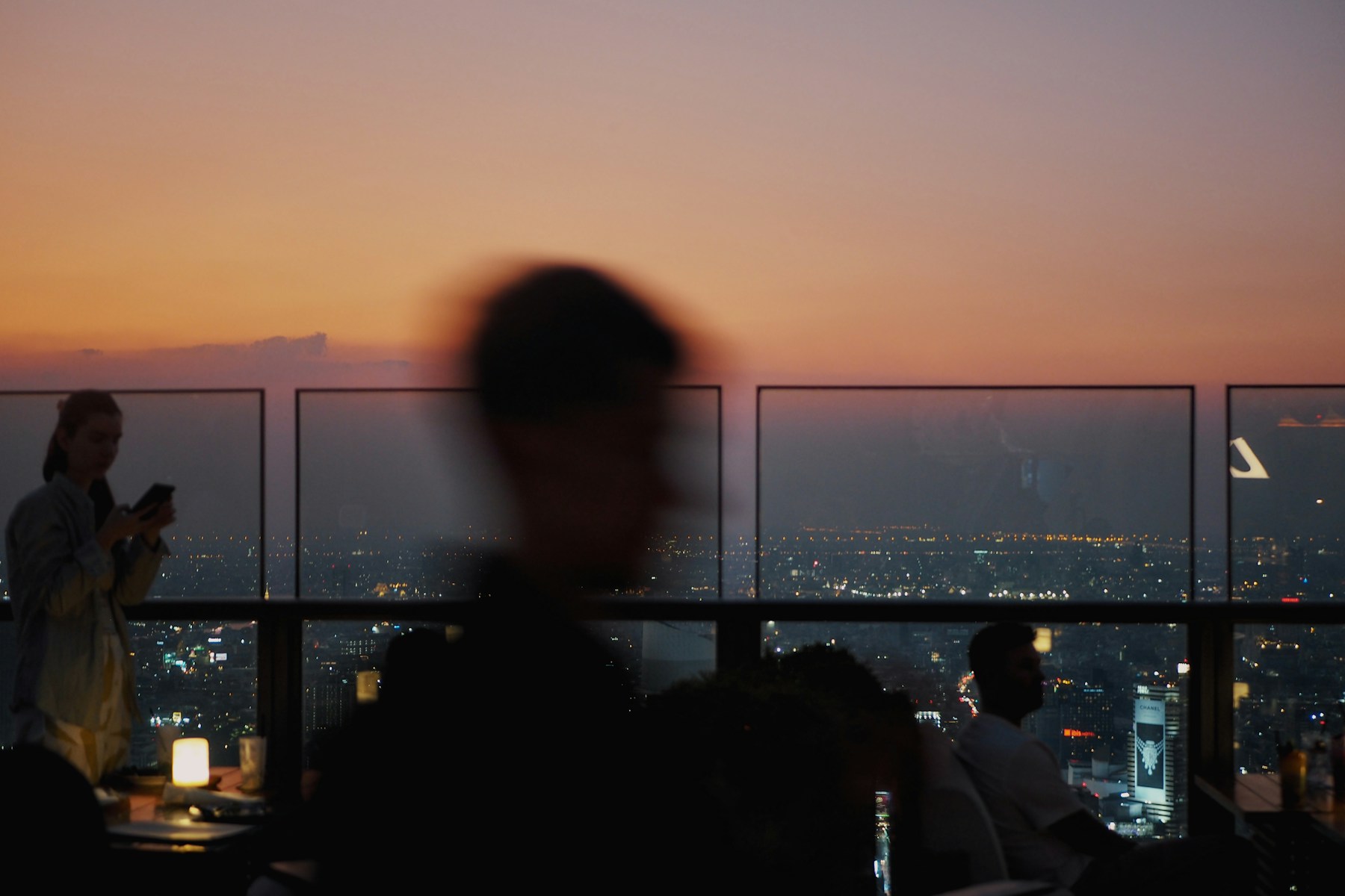 Guests at a Bangkok rooftop bar as the sun sets