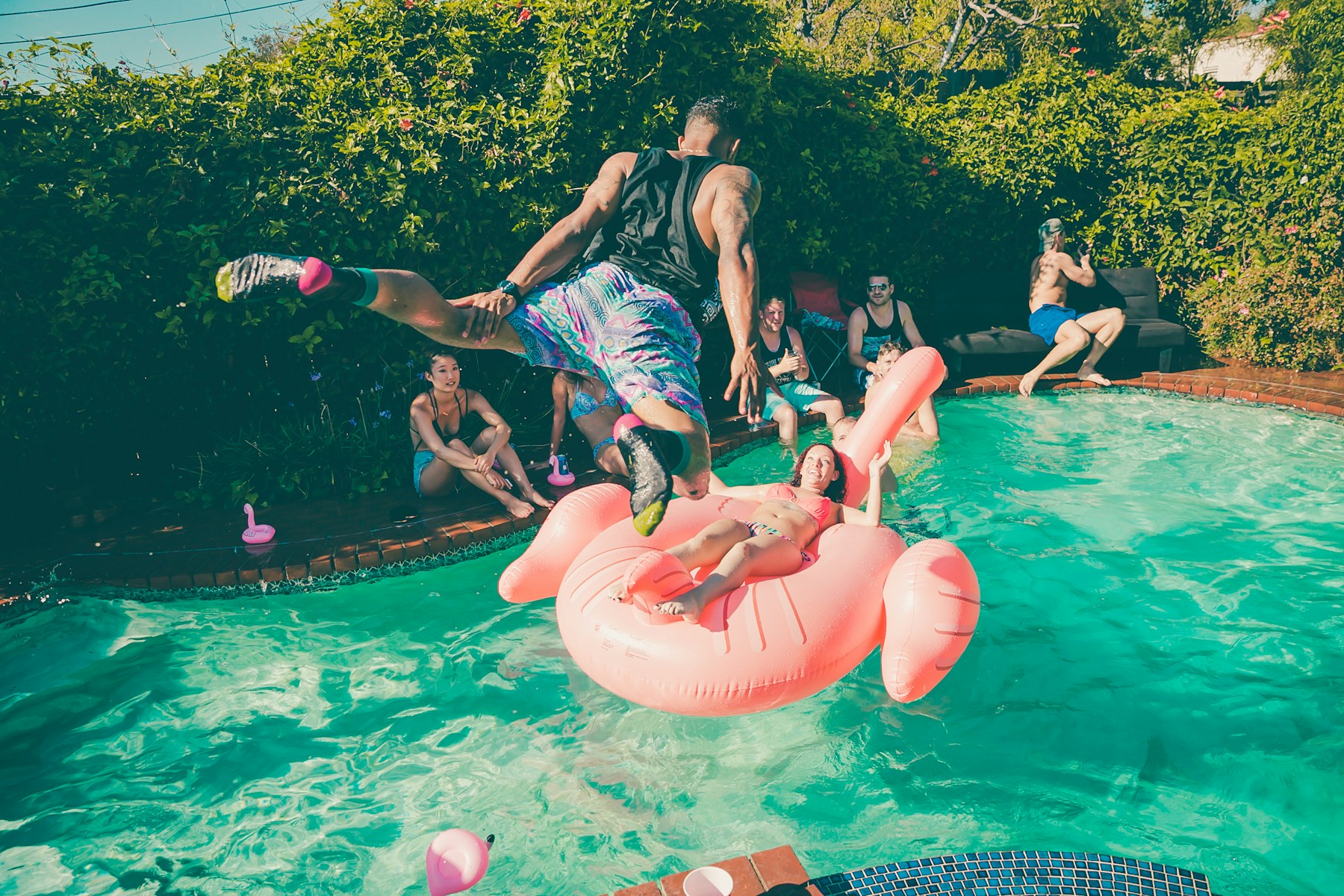 Friends enjoying a sunny pool party with colorful floats